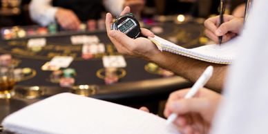 Person timing and noting results at a poker table.