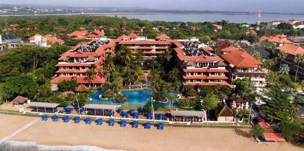 A beachfront resort with red-roofed buildings and a pool.