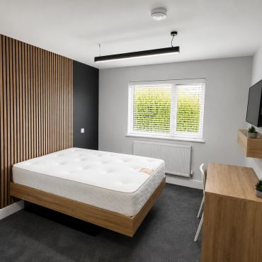 Minimalist bedroom with wooden accents and modern furnishings.