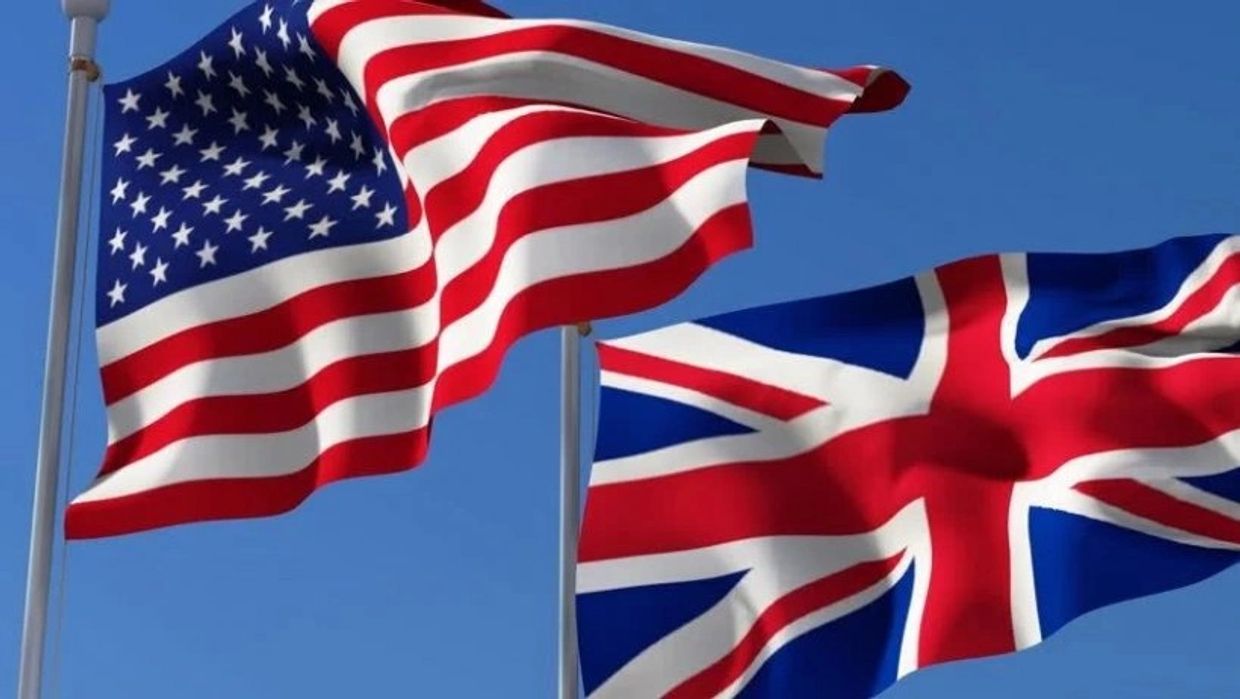American and British flags waving against a clear blue sky.