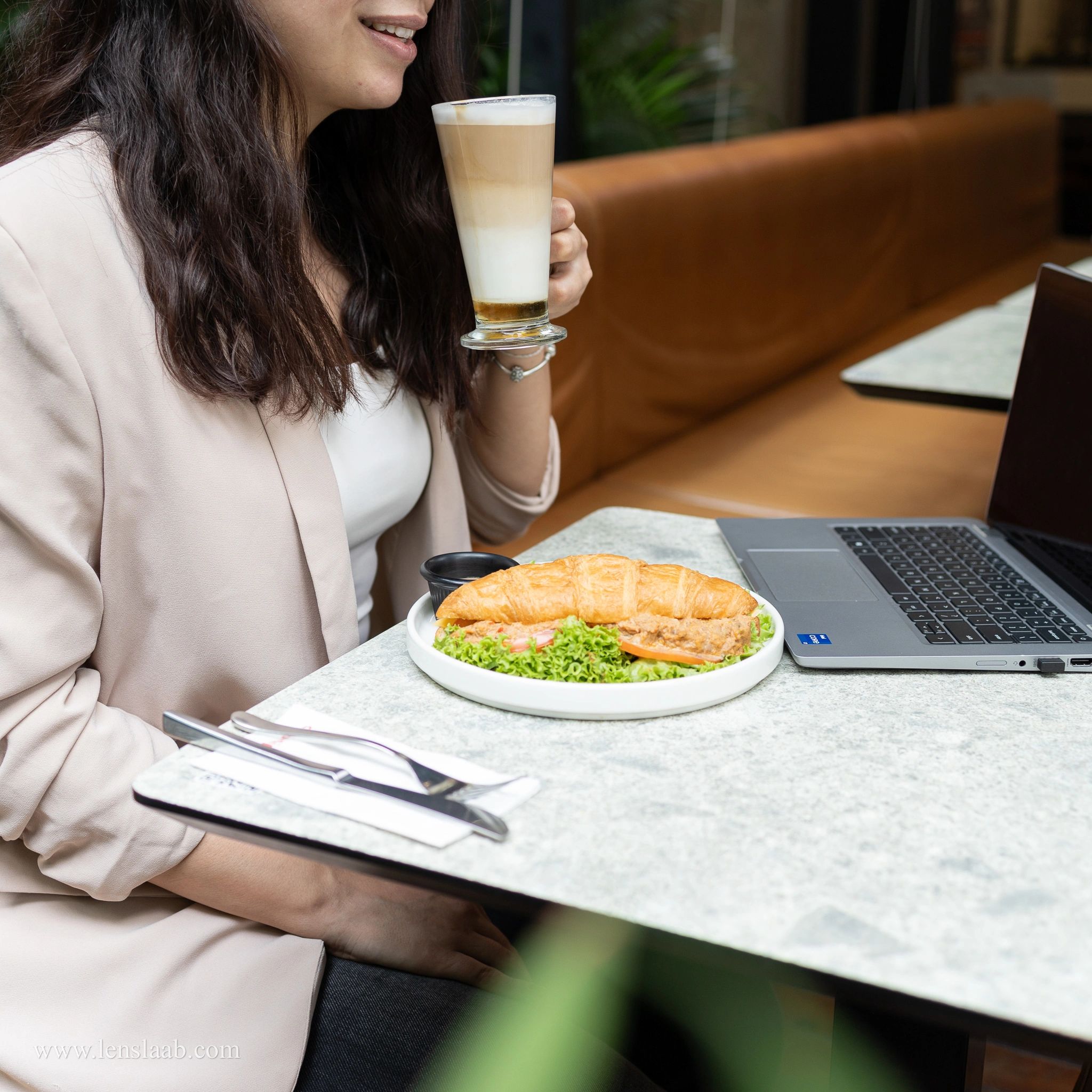 a woman drinking coffee and eating breakfast on a business meeting and laptop on the table