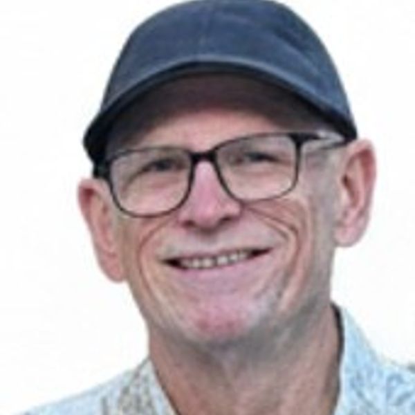 Smiling man wearing a cap and glasses.