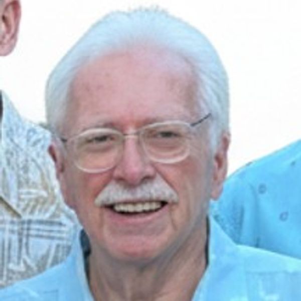 Smiling elderly man with white hair and glasses.