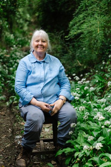 Devon flower grower Pat, sits among the wild garlic, in the lane to her farm