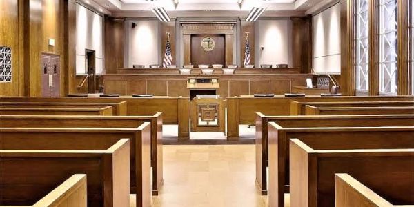 Empty courtroom with wooden benches and judge's bench.