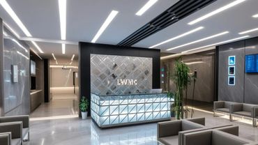 Modern, sleek medical or office reception area with illuminated desk and seating.