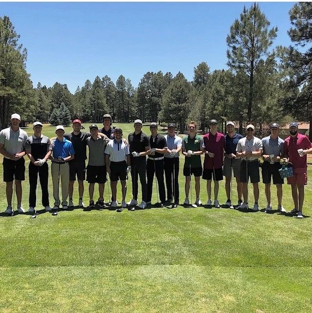 Group of men posing on a golf course.