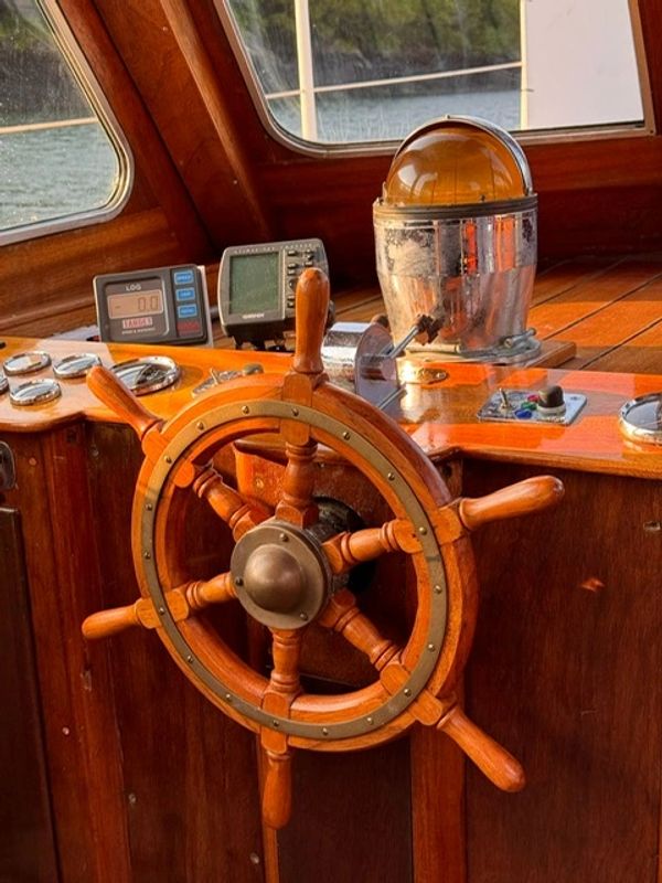 Wooden ship wheel and navigation instruments on a boat.
