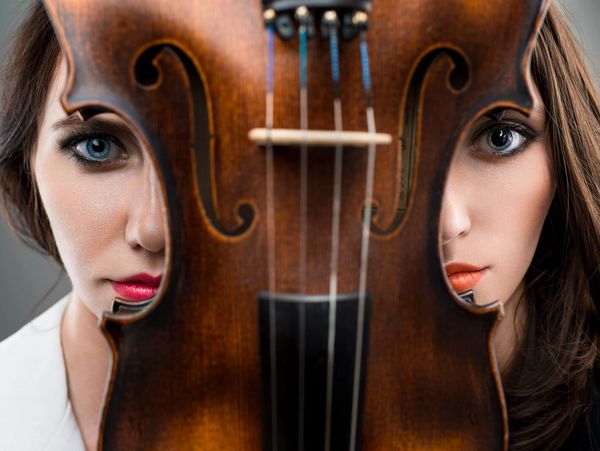 A pianist and violinist standing symmetrically behind a violin. 
