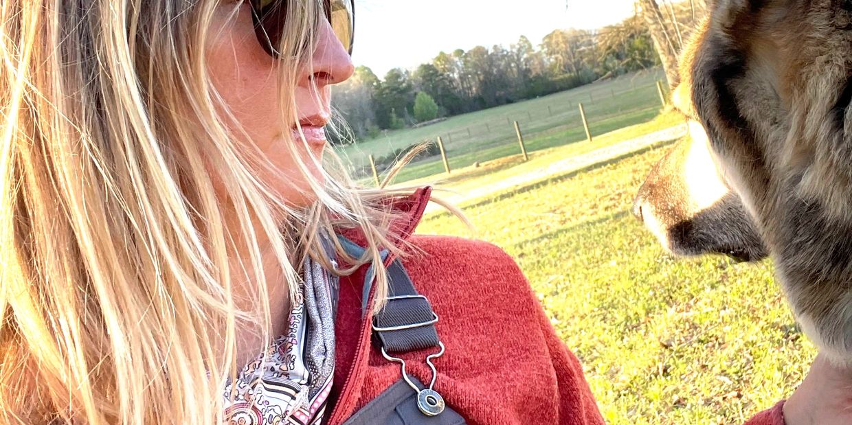 Woman in sunglasses with a dog outdoors.