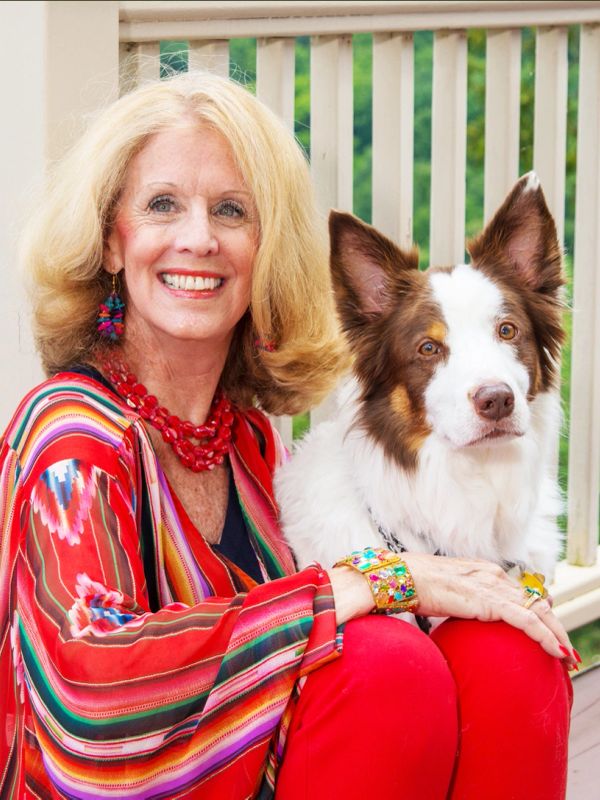Smiling woman with a dog, both sitting outdoors.