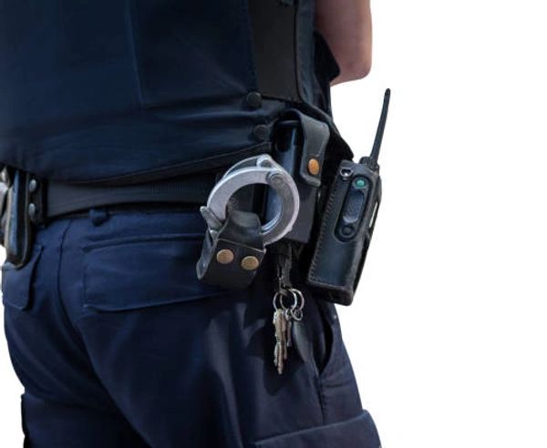 Close-up of a police officer's belt with handcuffs, keys, and a radio.