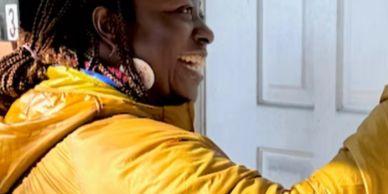 Person smiling warmly while engaging at a door.