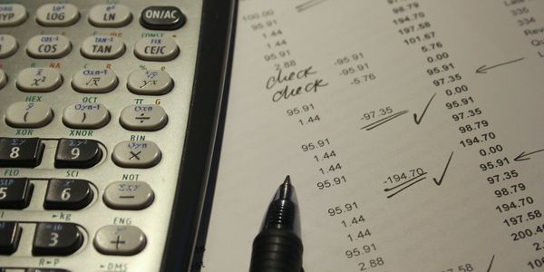 Calculadora e planilha financeira com notas manuscritas.