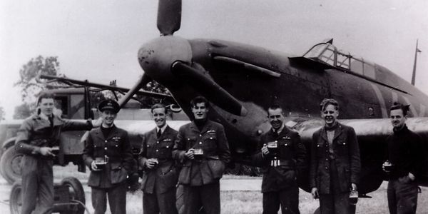 B-Flight, 85 Squadron, captured on film in June 1940 holding drinks in front of a Hurricane fighter.