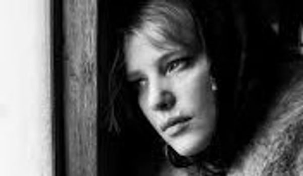Black and white portrait of a thoughtful woman gazing out a window.