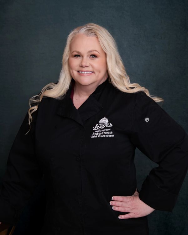 Smiling female chef in black coat.