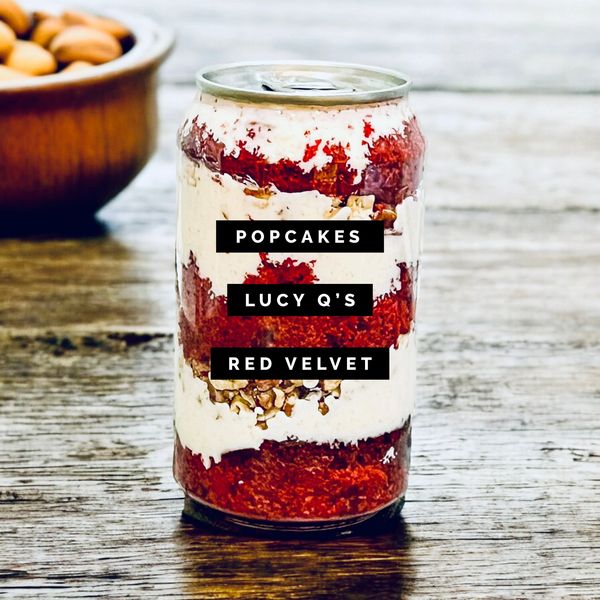 A red velvet popcake in a can labeled Lucy Q's on a wooden table.