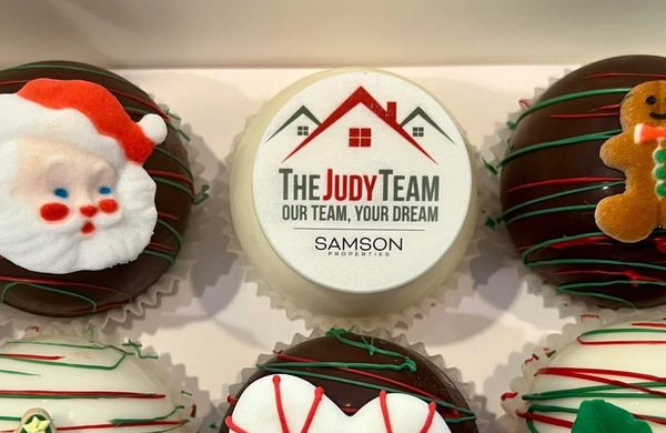Festive cupcakes with Christmas decorations and a branded cupcake in the center.