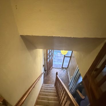 Narrow, carpeted staircase leading down to a wooden door with a glass window.