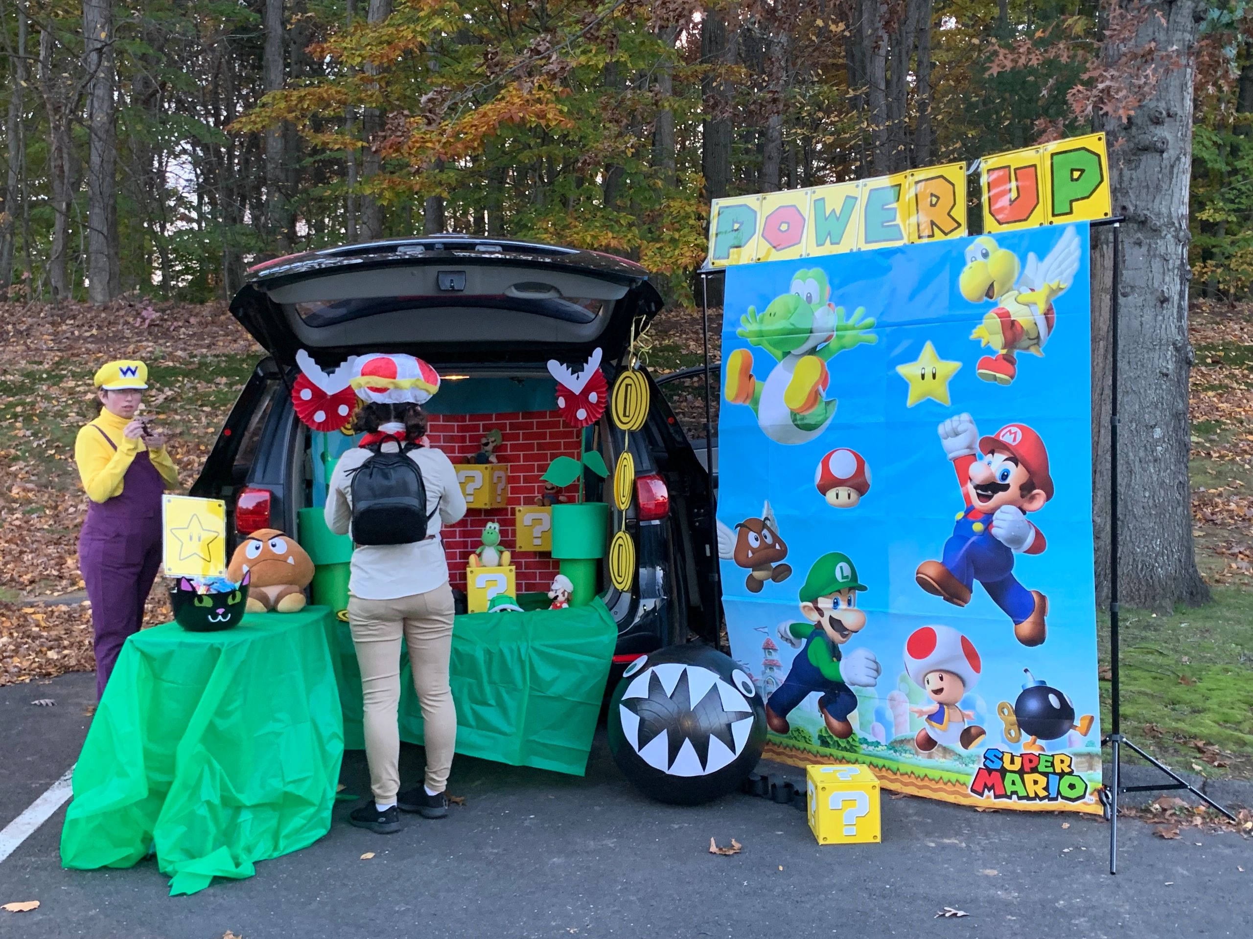 Super Mario-themed outdoor setup with characters and decorations around a car trunk.