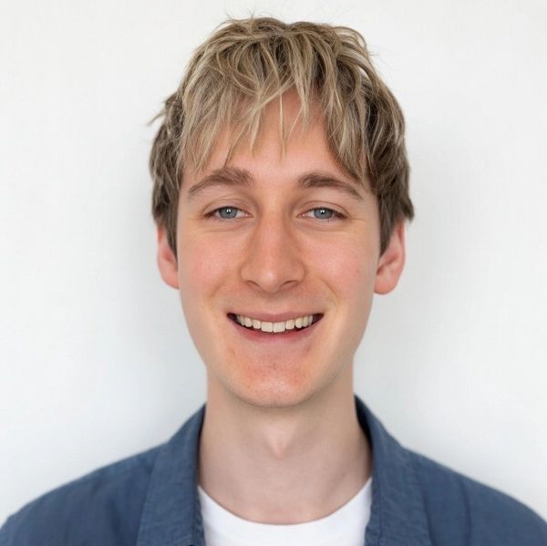 Smiling young man with blonde hair wearing a blue shirt and white t-shirt.