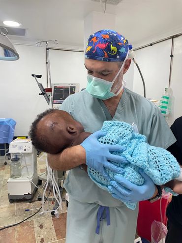 Anesthesia personnel carrying an infant who just had a shunt placed for hydrocephalus.