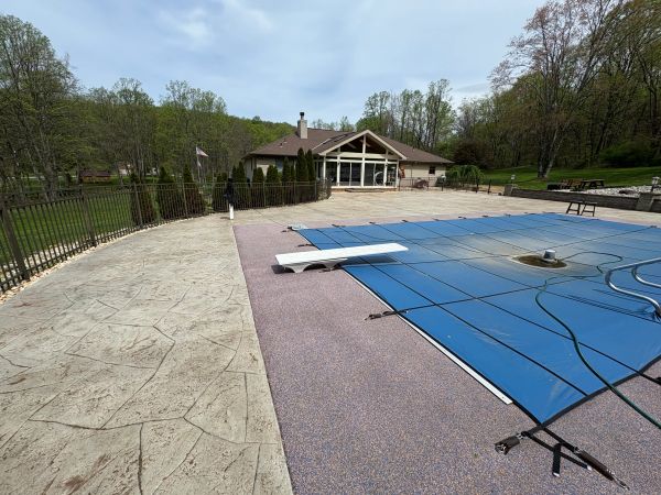 Covered outdoor swimming pool next to a house with surrounding trees.