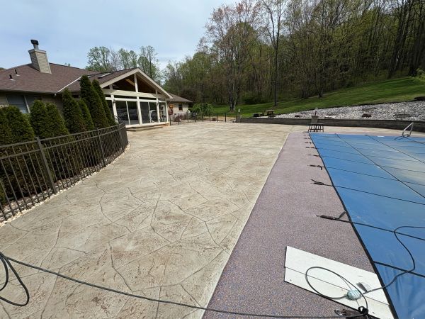 A backyard patio with stamped concrete next to a covered pool.