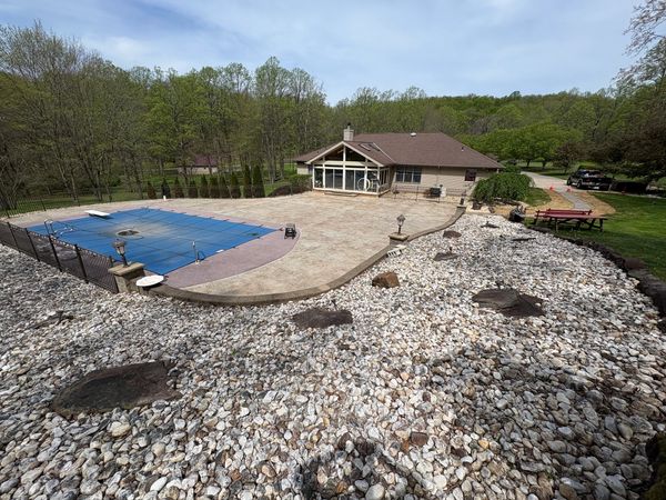 House with a covered pool and a large stone-covered yard.
