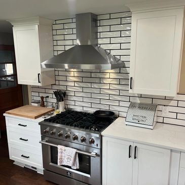 Modern kitchen with stainless steel stove and white cabinetry.
