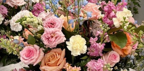 A vibrant bouquet of mixed pastel flowers including roses and carnations.