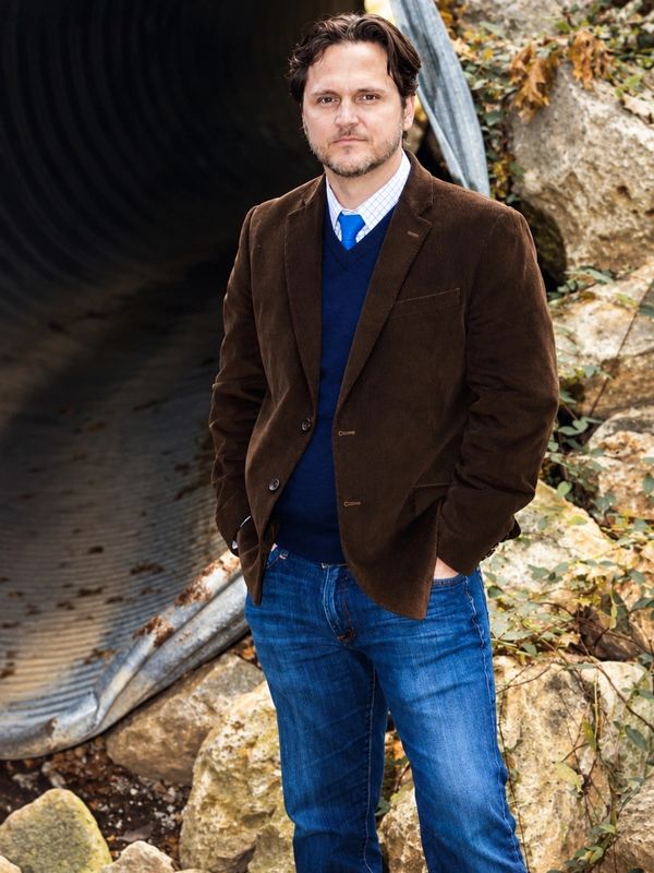 Man standing outdoors near a tunnel.