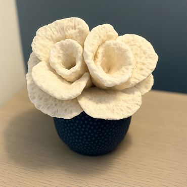 White textured flowers in a blue vase on a wooden table.