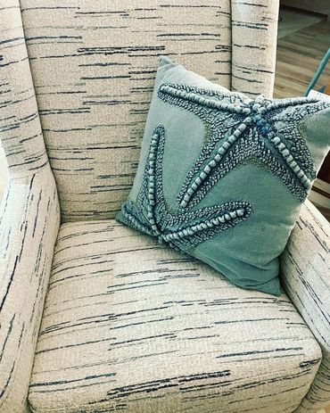 Beige armchair with a blue starfish-patterned cushion.