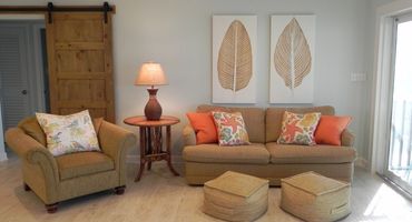 Cozy living room with beige sofa, armchair, and tropical-themed cushions.