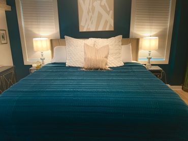 Elegant bedroom with a teal bedspread and soft lighting from bedside lamps.
