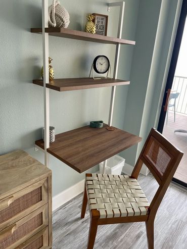 Modern wooden desk setup with a chair and decorative shelves.
