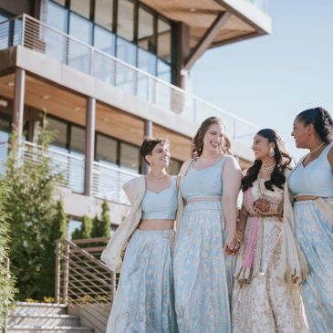Four women in light blue traditional dresses walking and smiling outdoors.