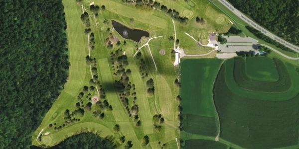 Aerial view of a golf course surrounded by trees and farmland.