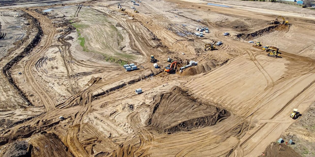 A large construction site with heavy machinery and piles of dirt.