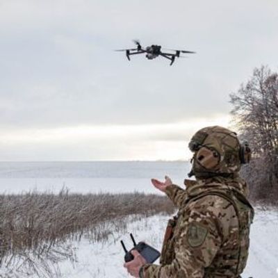 Soldier operating a drone in a snowy field.