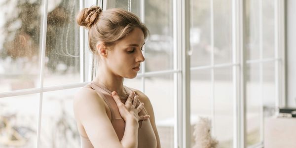 a woman holding her hands to her chest and stomach with eyes closed