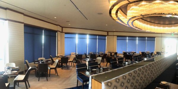 large resort dining room with blue and white chairs with large chandelier and navy blue shades