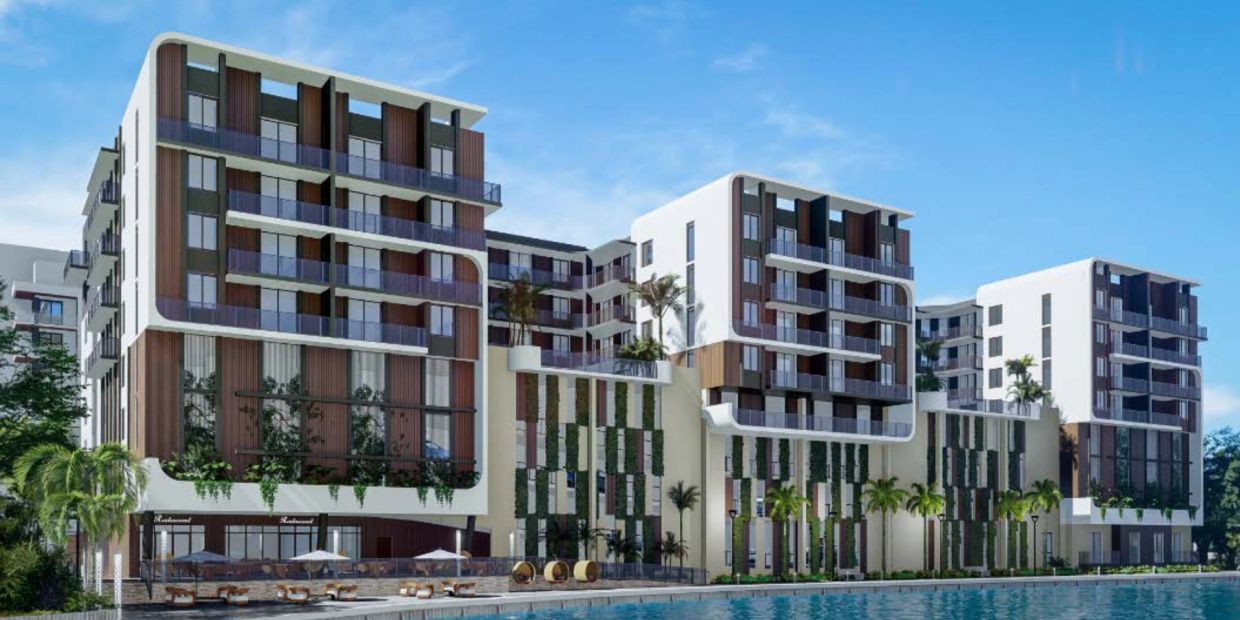 Modern residential building by the water with balconies and greenery.
