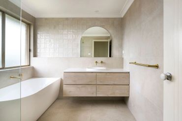Modern bathroom with floating vanity, bathtub, and gold fixtures.