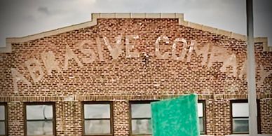 Photo of "Abrasive Company" painted on the side of an old brick building.