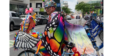 Creatively dressed person on a blue bicycle. Butterfly print clothing and accessories.