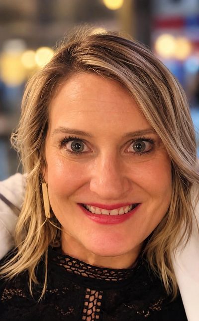 Close-up of a smiling woman with blonde hair and blue eyes.