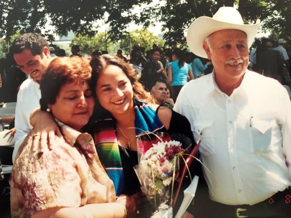 Young woman celebrating with her parents outdoors.